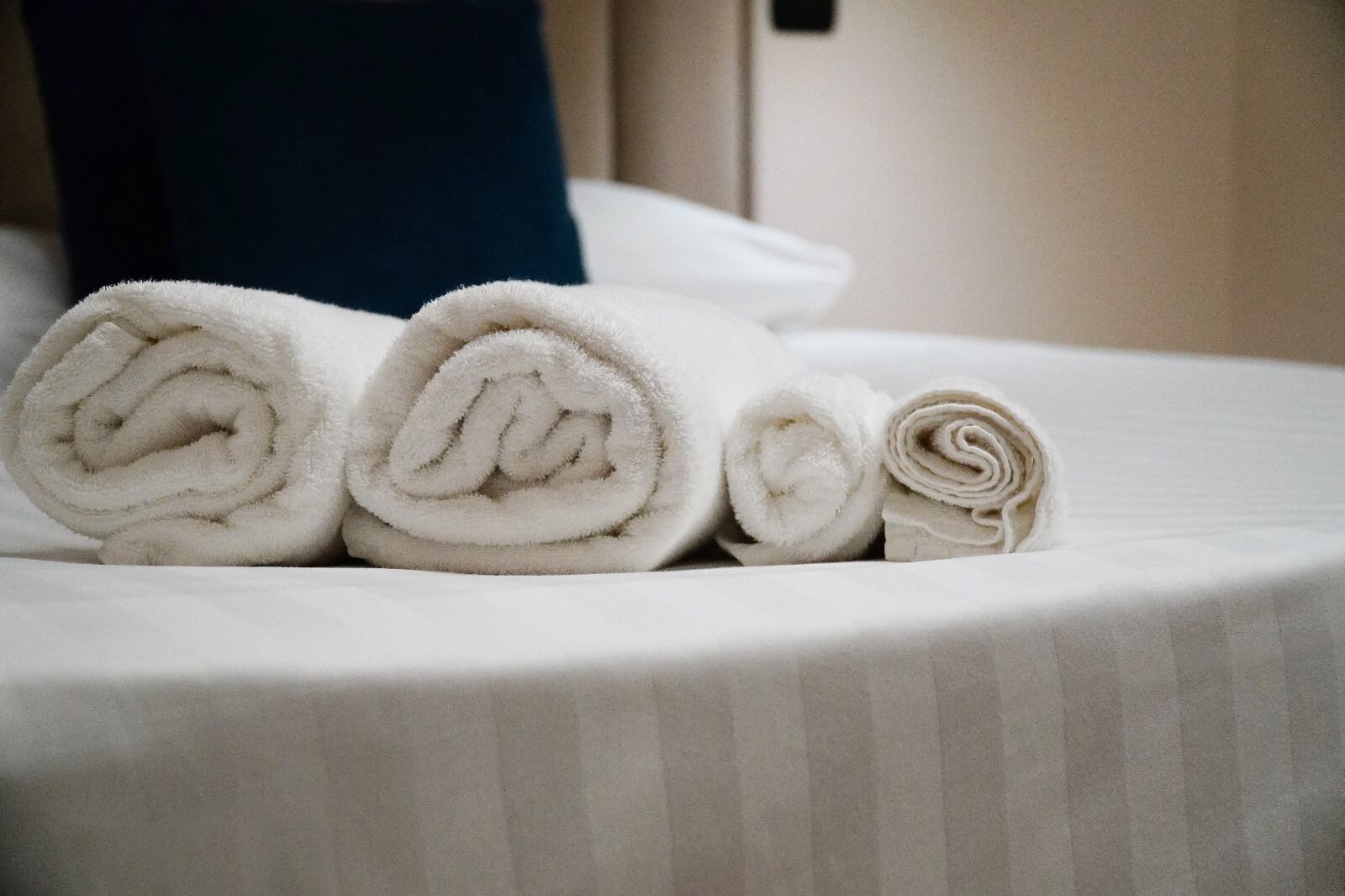 A neatly made bed with rolled white towels.