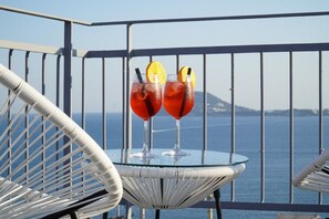 Two cocktails on a glass table with a view of the sea and a distant island. - Puteoli Palace Hotel (Pozzuoli)