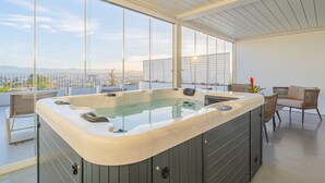 A modern indoor hot tub area with a panoramic city view, large windows, and a seating area with wicker furniture. - Felix Hotels - Hotel Felix Olbia (Olbia)