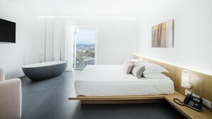A modern hotel room with a large bed, a built-in bathtub, a bedside phone, and a city view through the window. - Felix Hotels - Hotel Felix Olbia (Olbia)