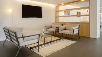 A modern living room with a sofa, armchairs, a coffee table, and a flat-screen TV mounted on the wall.