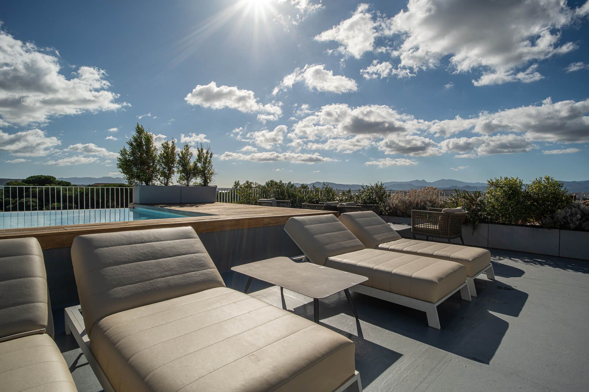 A rooftop terrace with outdoor seating, a pool, and a view of mountains.