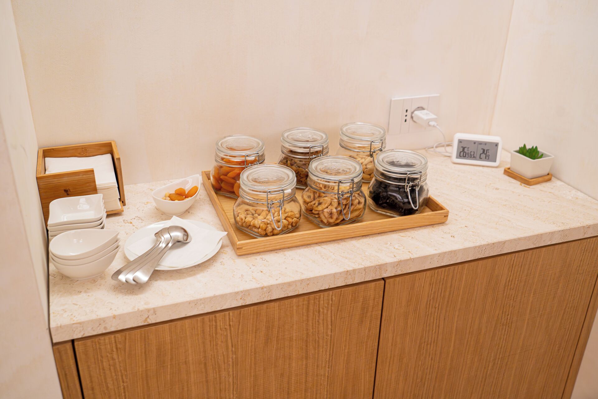 A kitchen counter with jars of nuts and a digital clock.