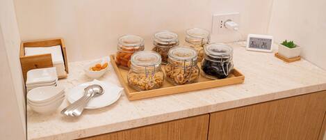 A kitchen counter with jars of nuts and a digital clock.