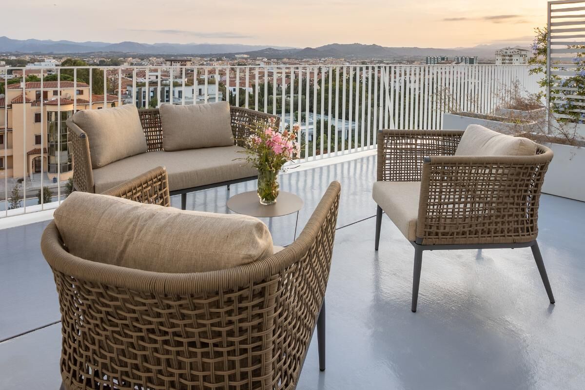 A balcony with wicker furniture, a small round table, and a vase with flowers.