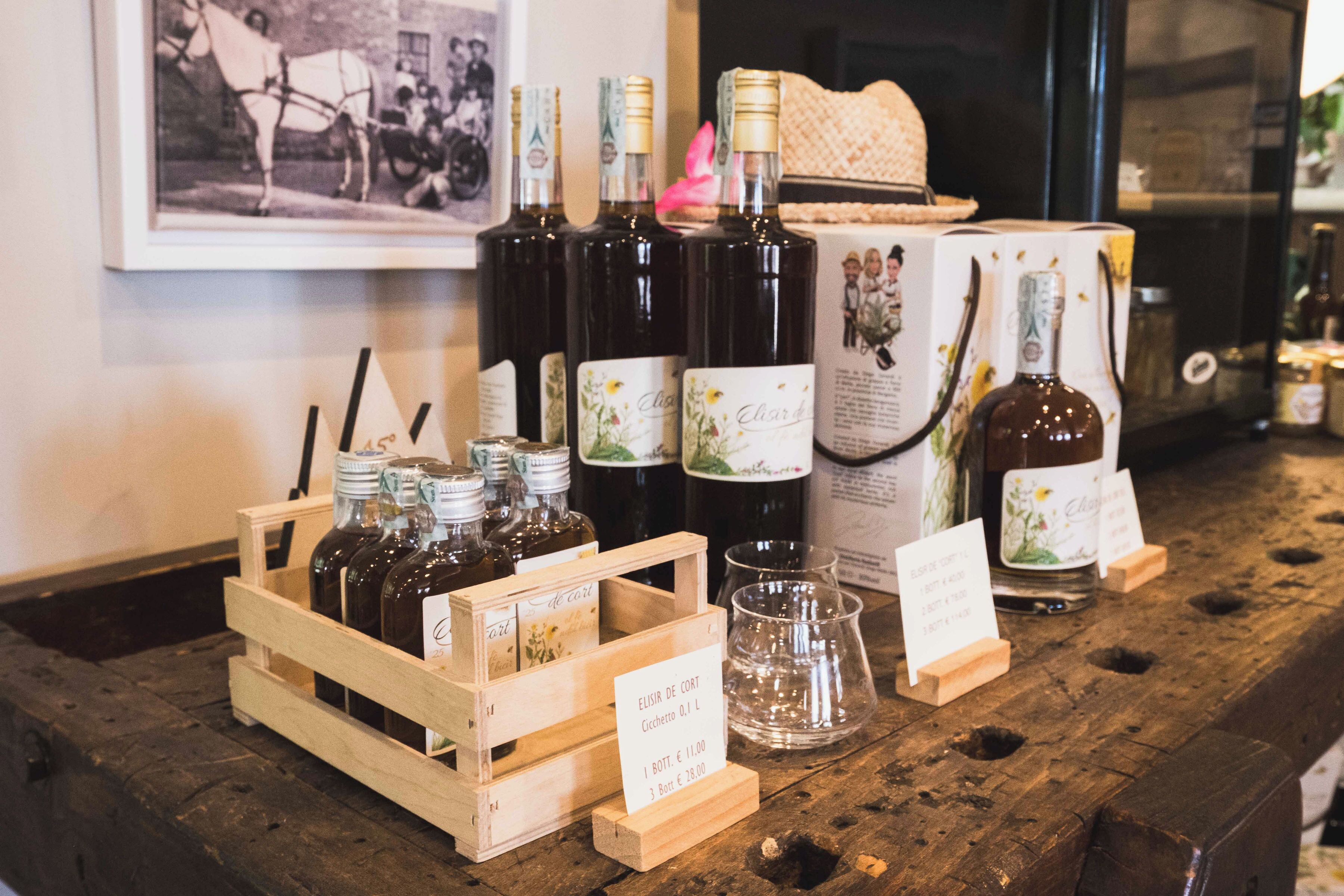 A wooden crate with wine bottles and glasses, a vintage photograph, and a sign indicating wine prices.