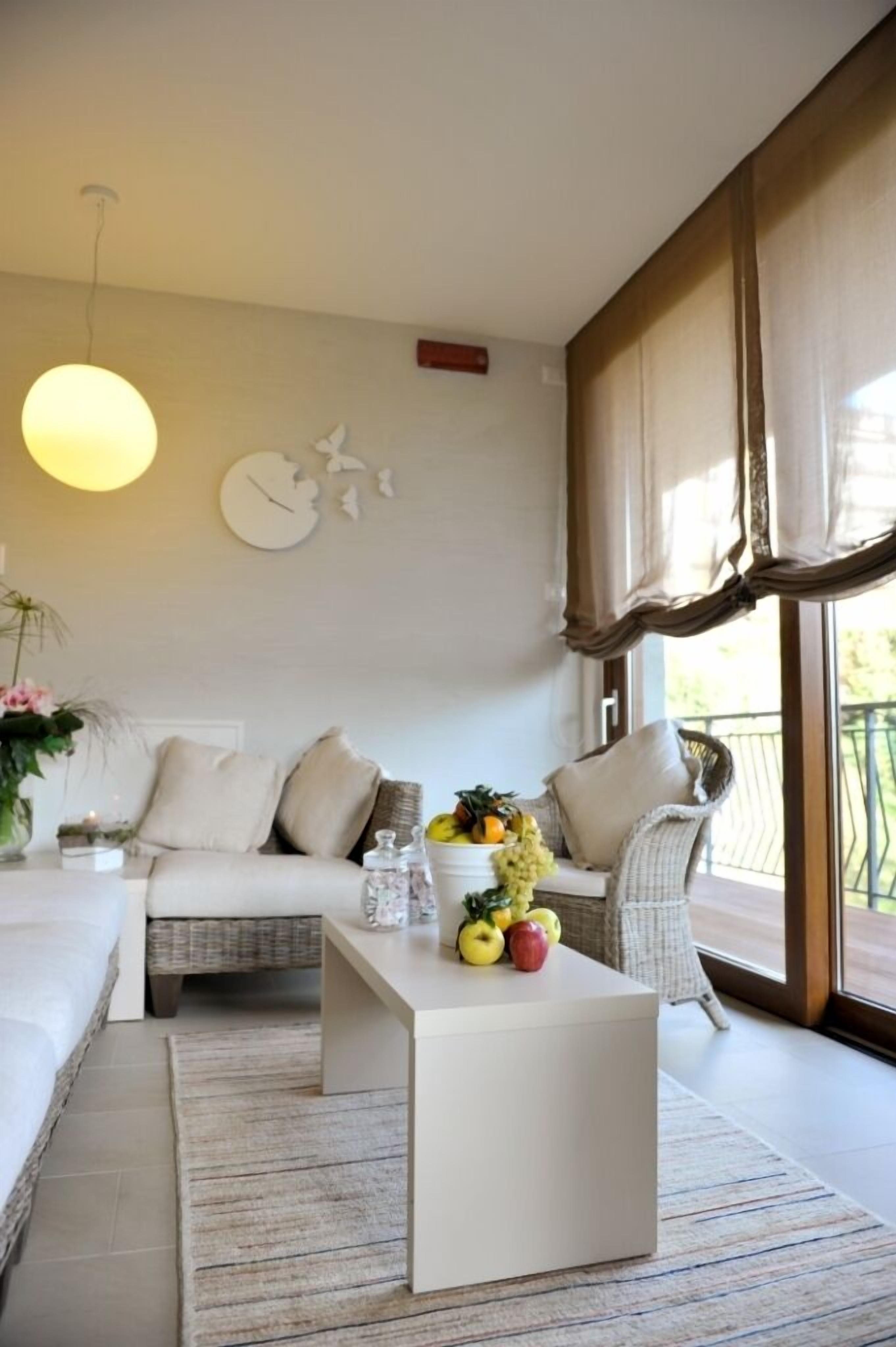 A modern living room with a sofa, a coffee table, and a large window with curtains.