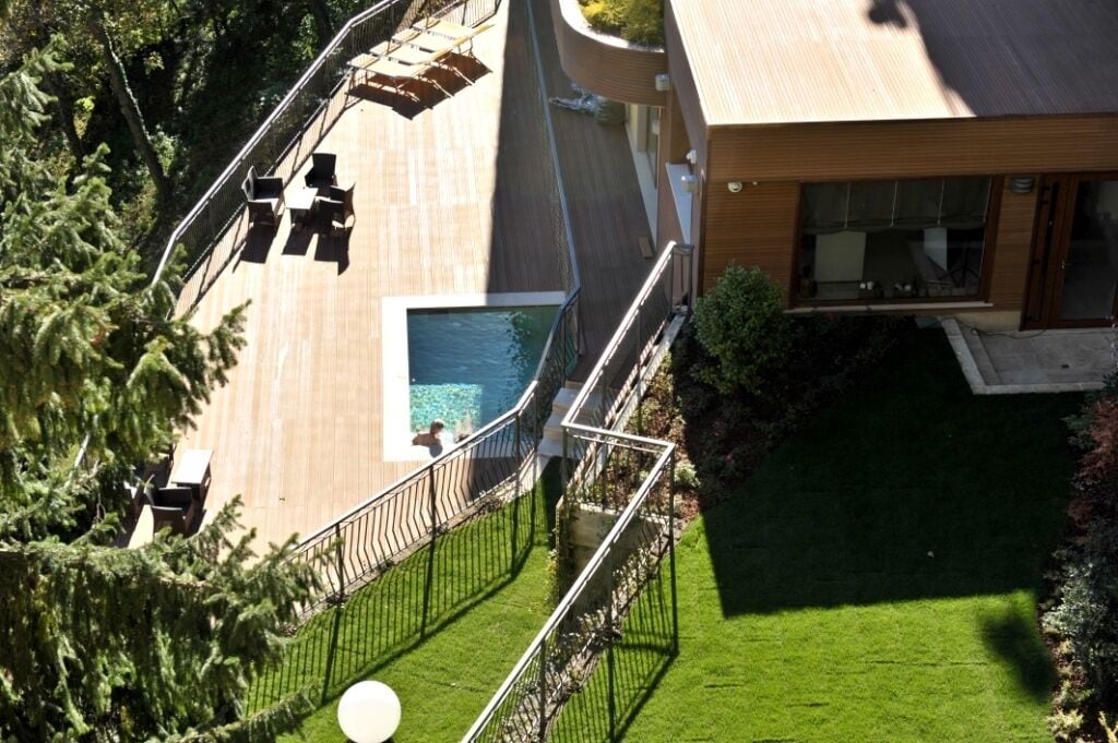 A modern house with a swimming pool, a deck, and a well-maintained lawn.