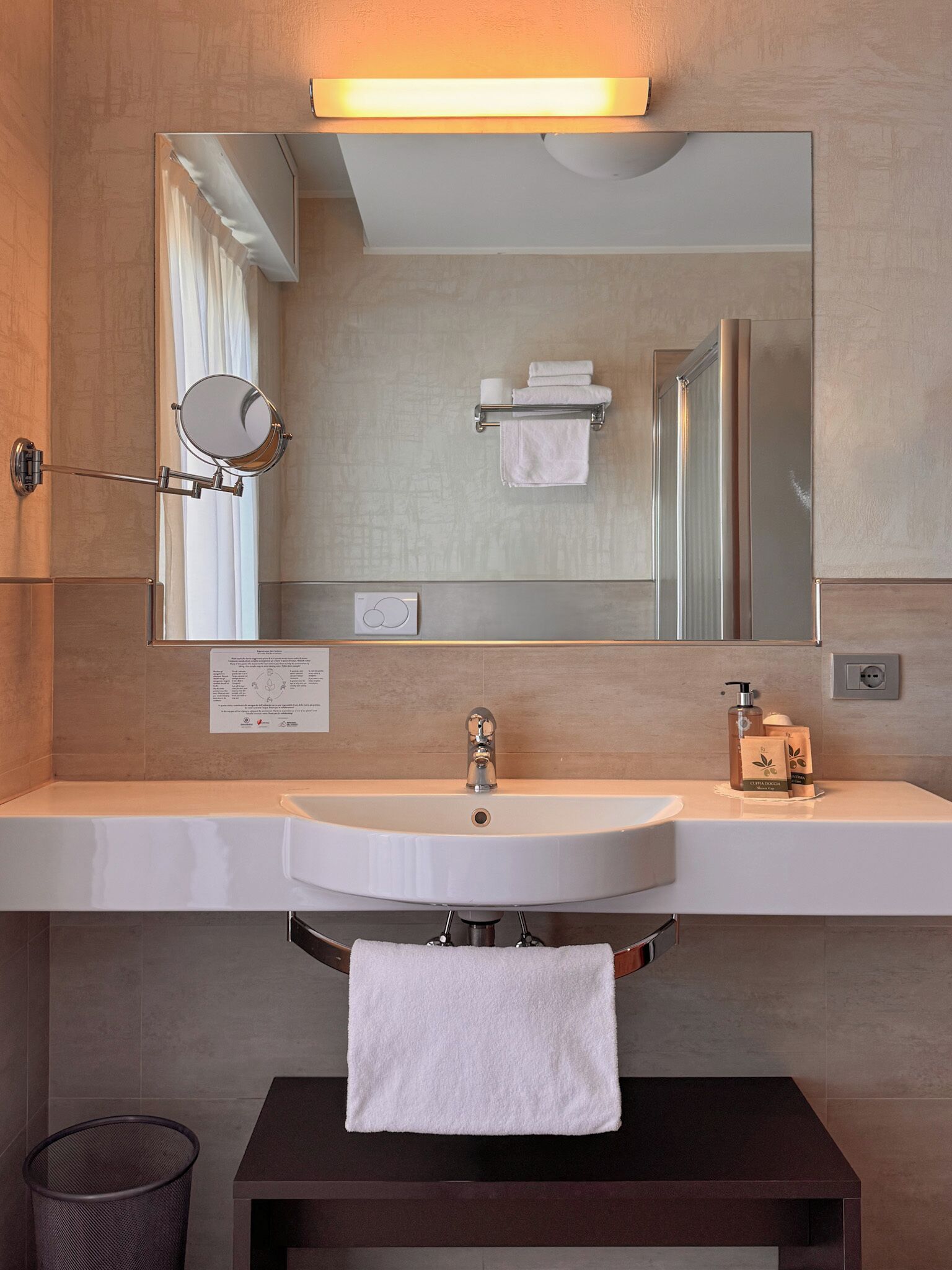 Une salle de bain moderne avec un lavabo blanc, un miroir et un porte-serviettes.