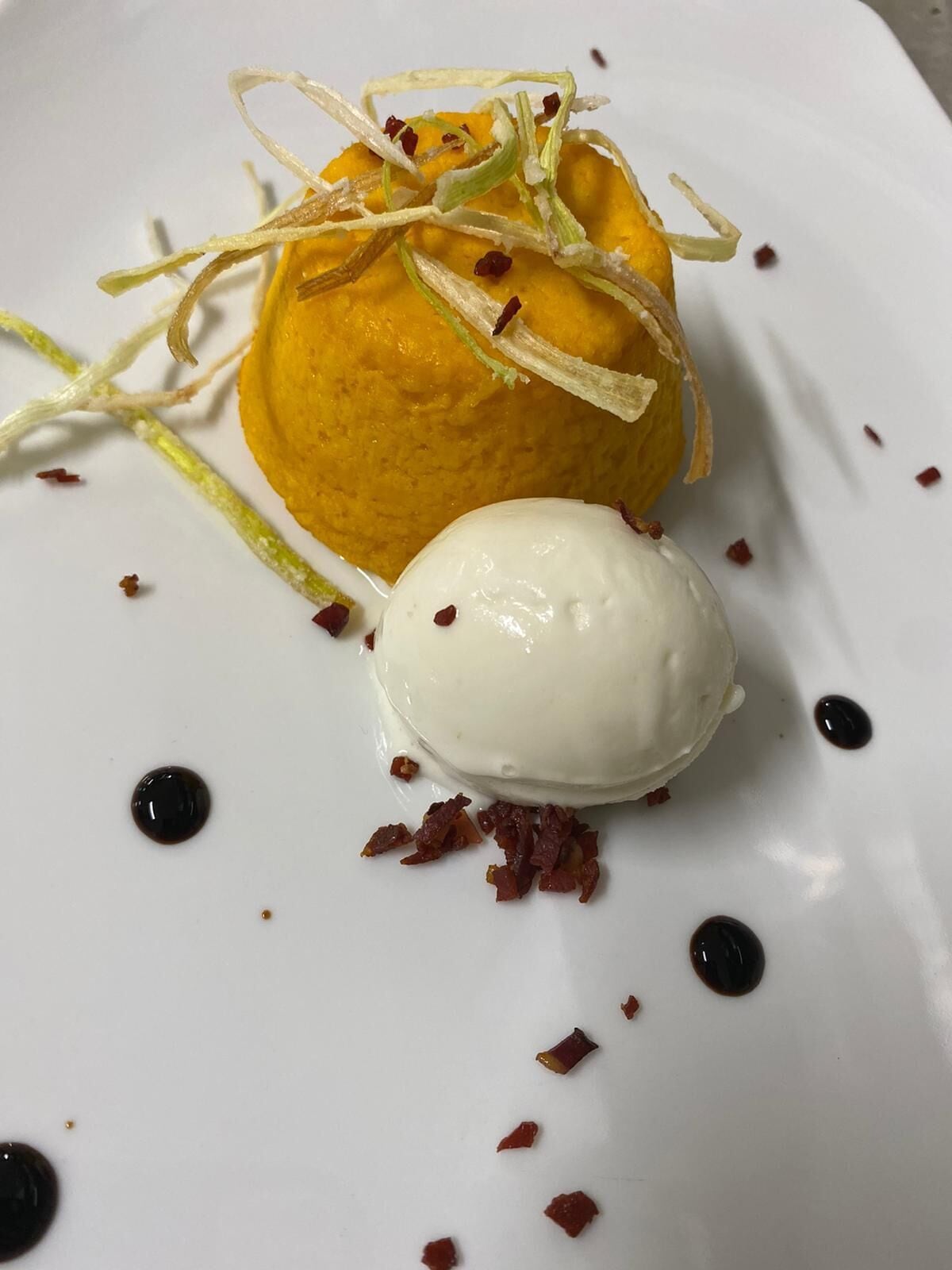 Postre amb una bola de gelat sobre un plat blanc.