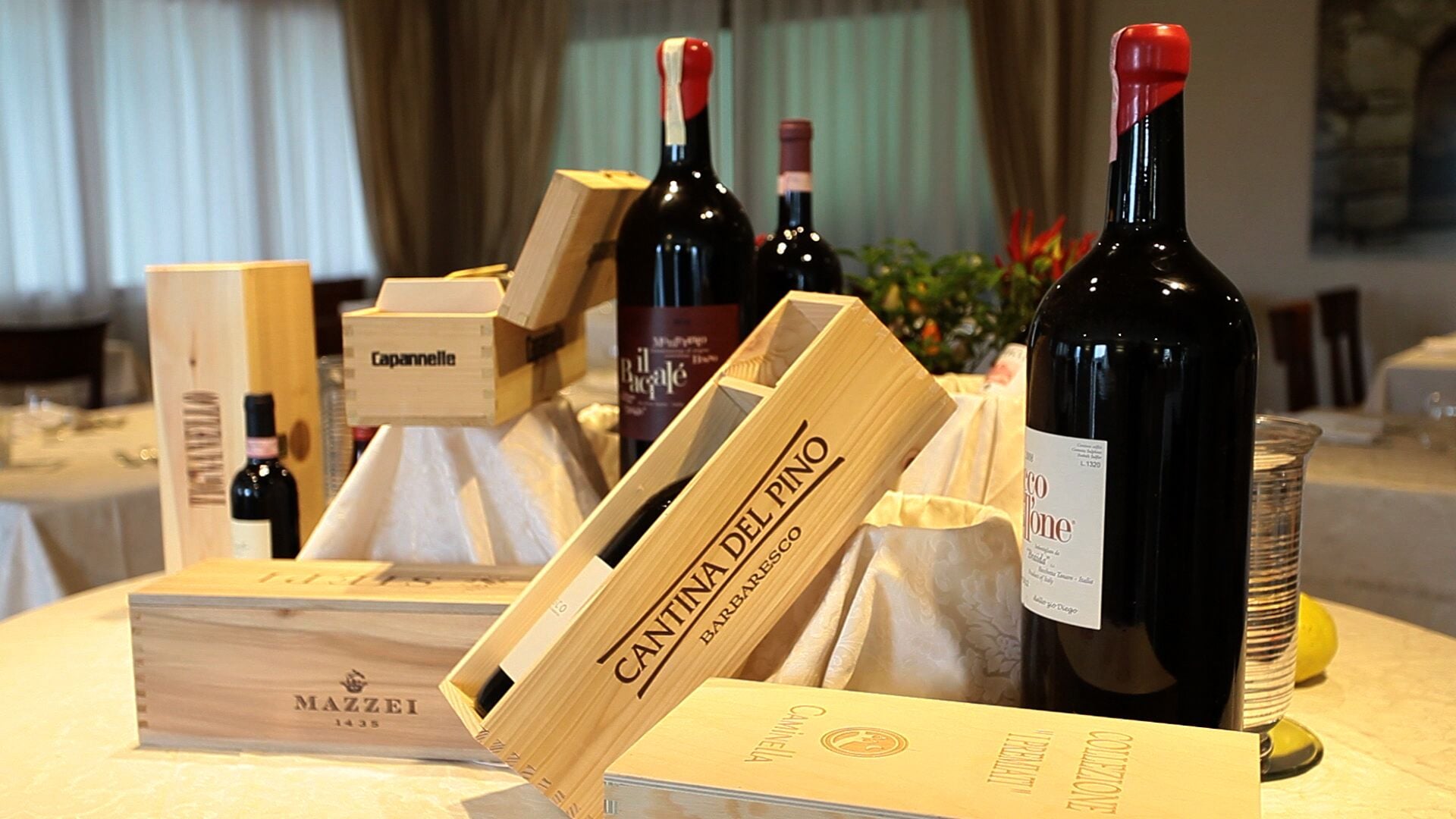 A selection of wine bottles and boxes on a table, with labels such as "Cantina del Pino" and "Mazzei."