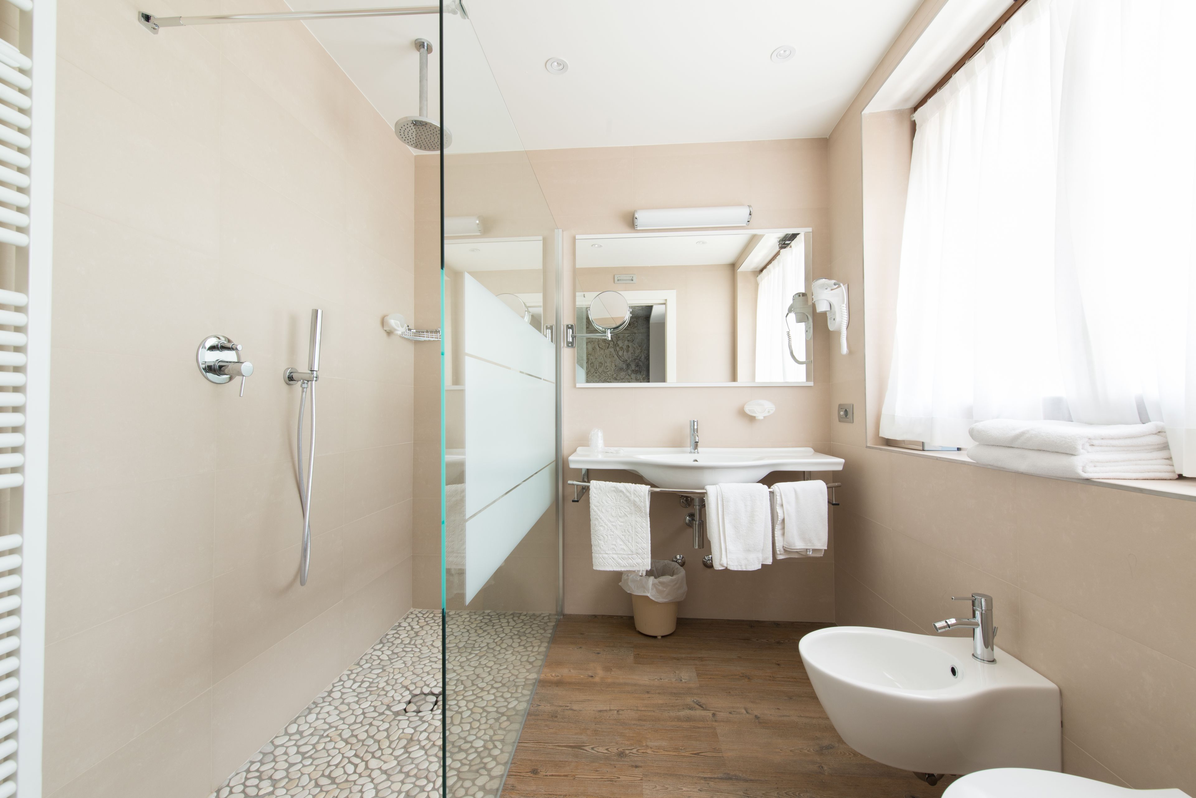 A modern bathroom with a glass shower enclosure, a sink with a mirror, and a bidet.
