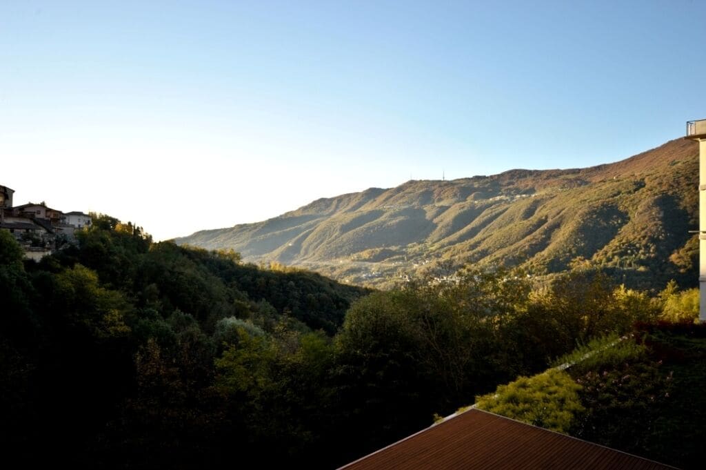A hillside view with a building on the right and a valley below.
