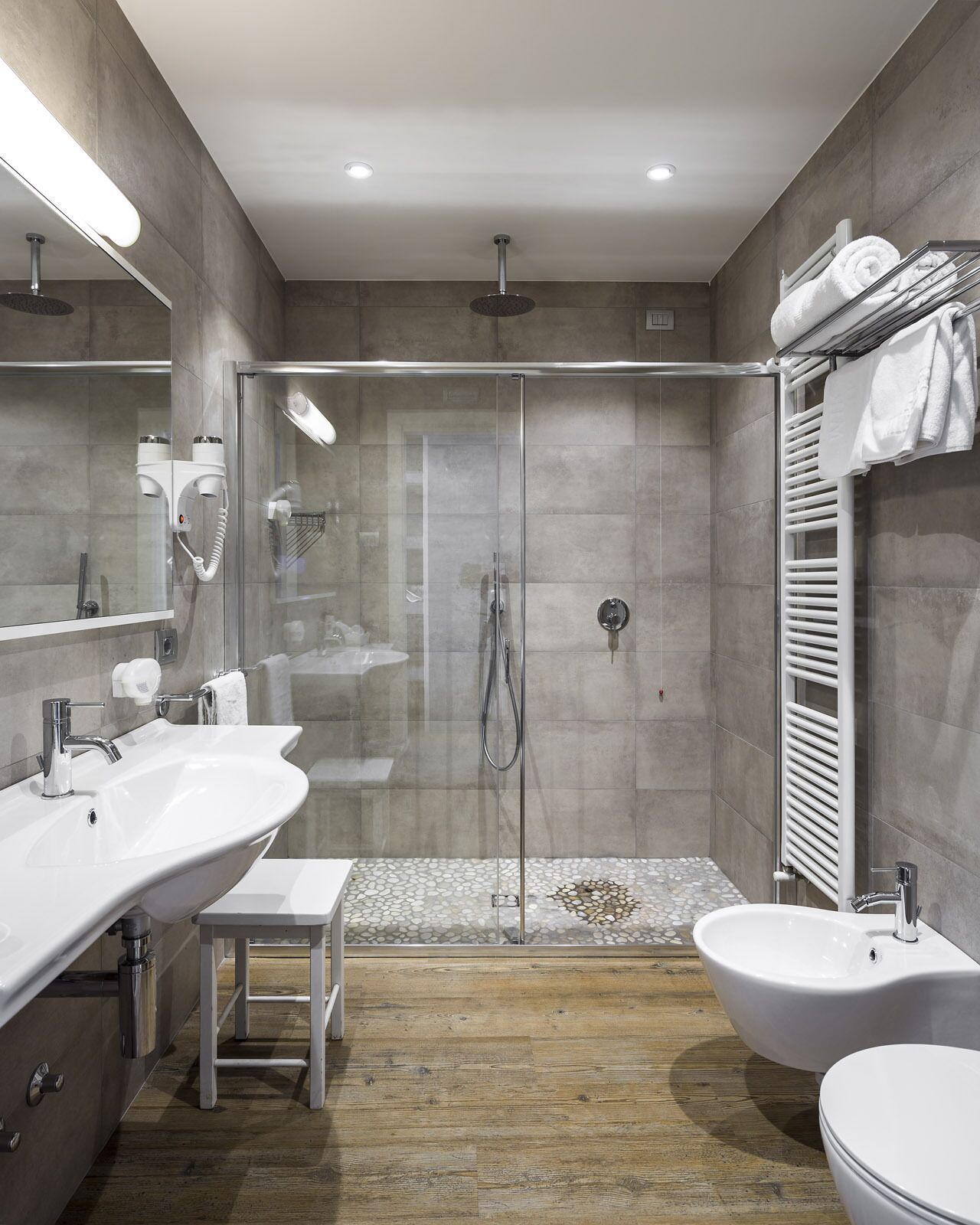 A modern bathroom with two sinks, a shower, and a toilet.