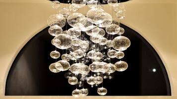 A chandelier with multiple clear glass orbs hanging from a black ceiling. Below the chandelier, there is a sign with the text "Carreira Bio-spa".