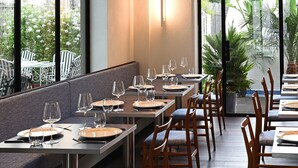 A restaurant with long tables, chairs, and a view of greenery outside. - Grand Hotel Flora (Sorrento)