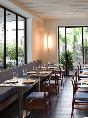 A restaurant with long tables, chairs, and a view of greenery outside. - Grand Hotel Flora (Sorrento)