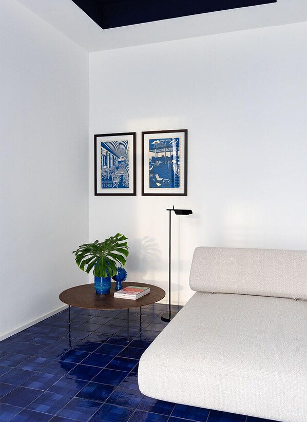 A modern room with a sofa, a small round table with a plant, and two framed pictures on the wall. - Grand Hotel Flora (Sorrento)