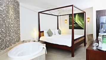 Una cama con dosel y estructura de madera, una bañera grande y un dispensador de agua instalado en la pared.