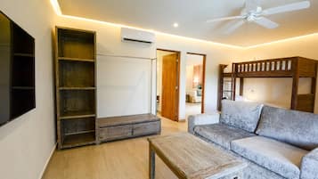 A modern living room with a sofa, a coffee table, a wooden bench, and a ceiling fan.