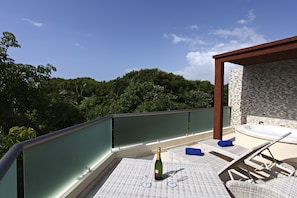 Relax on the outdoor terrace with a hot tub, seating area, and breathtaking views of the lush landscape.