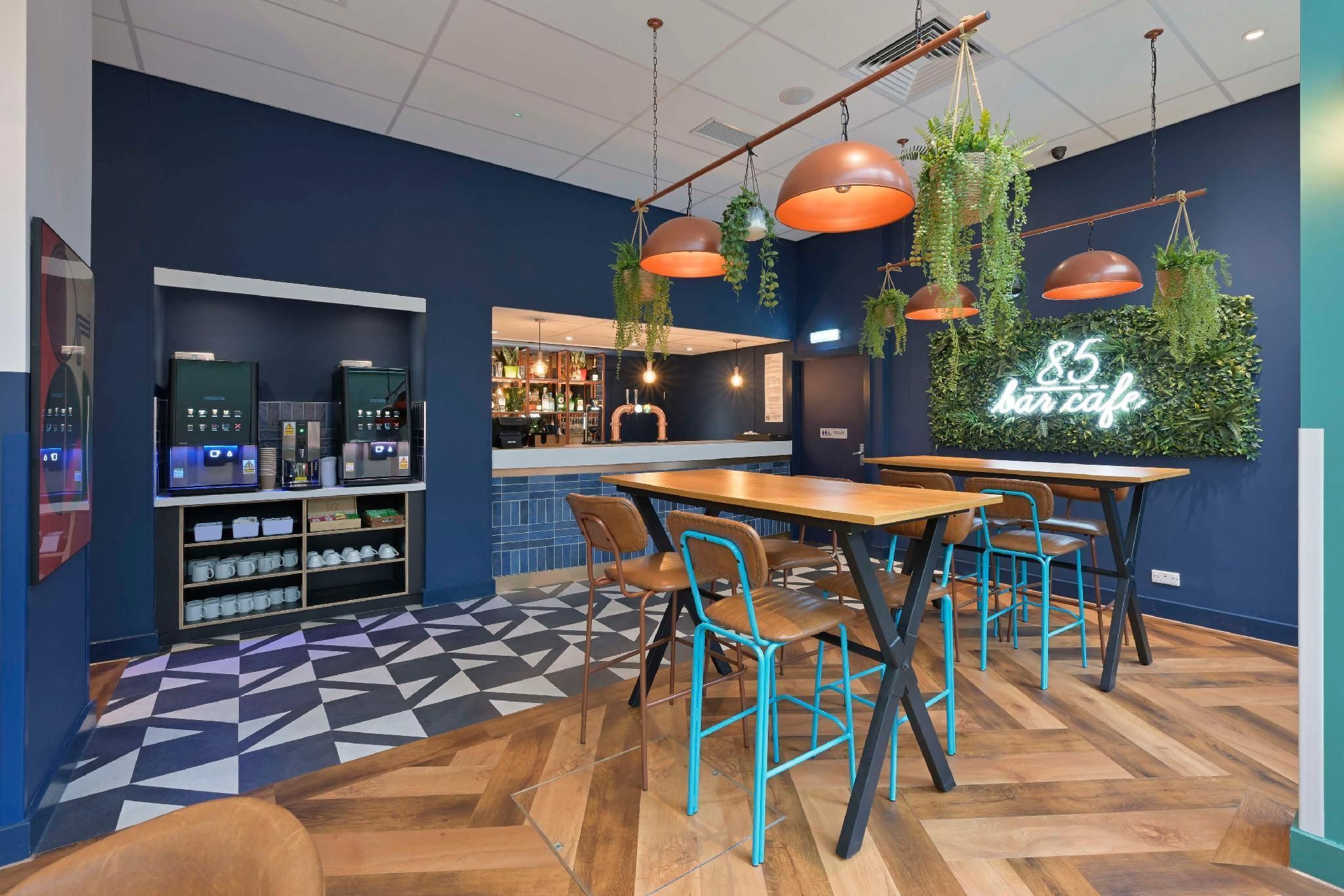 A modern cafe interior with a bar area, seating, and a neon sign.