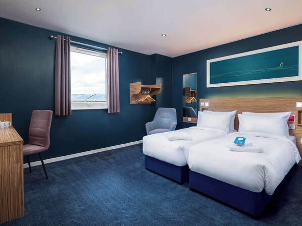 A hotel room with a large bed, a chair, a desk, and a window with curtains. - Travelodge Leeds Vicar Lane (Leeds)