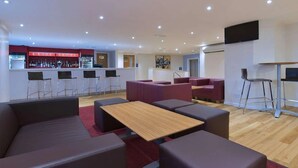 A modern lounge area with seating, a bar, and a flat-screen TV. - Travelodge Leeds Vicar Lane (Leeds)