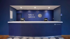 A reception desk with a 'hello & welcome' sign, a clock, and a 'Travelodge' logo. - Travelodge Leeds Vicar Lane (Leeds)