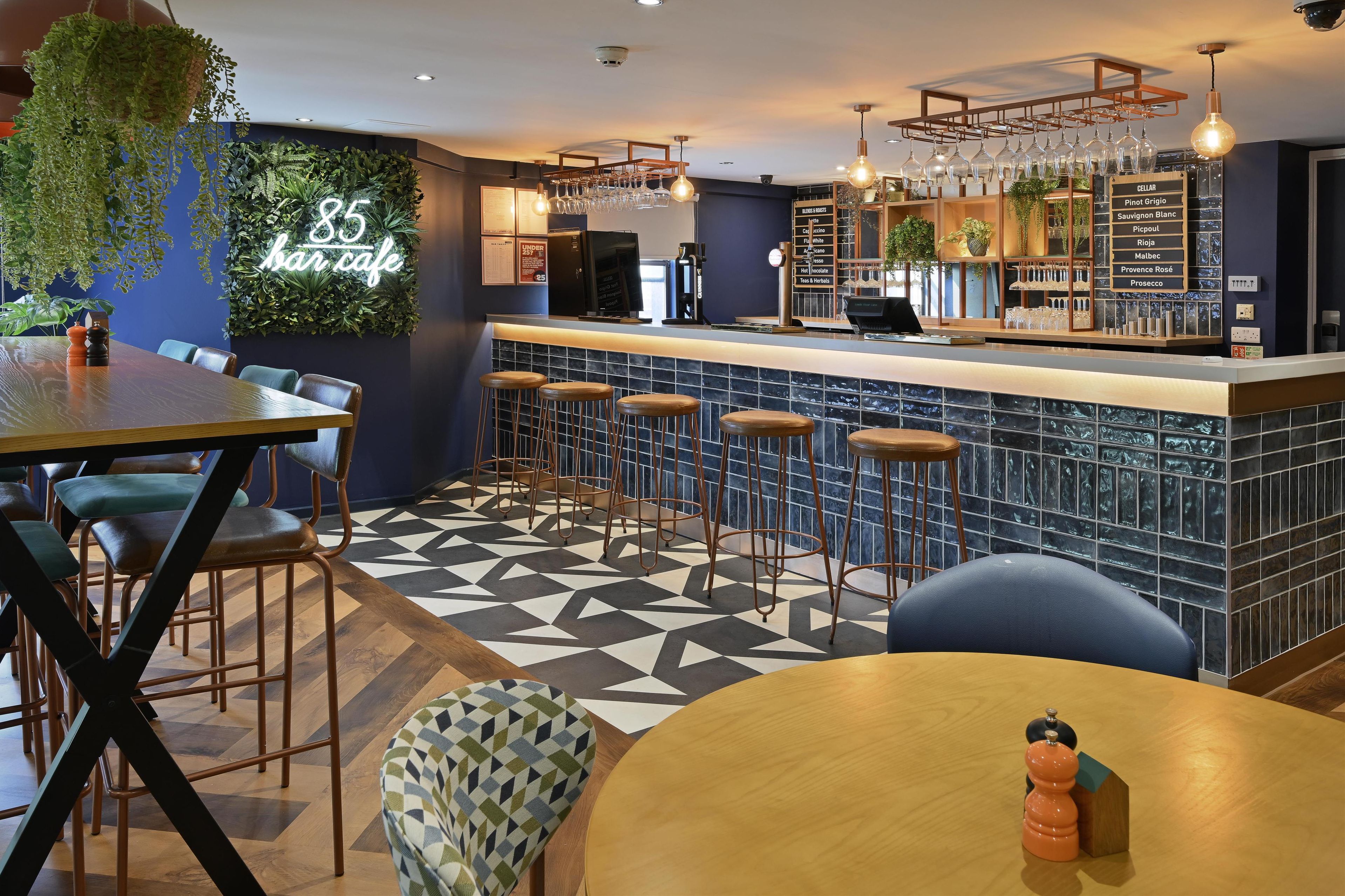 A bar area with a counter, stools, and a menu board listing drinks.