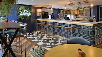Zona de bar con mostrador, taburetes y un panel con la carta de bebidas.