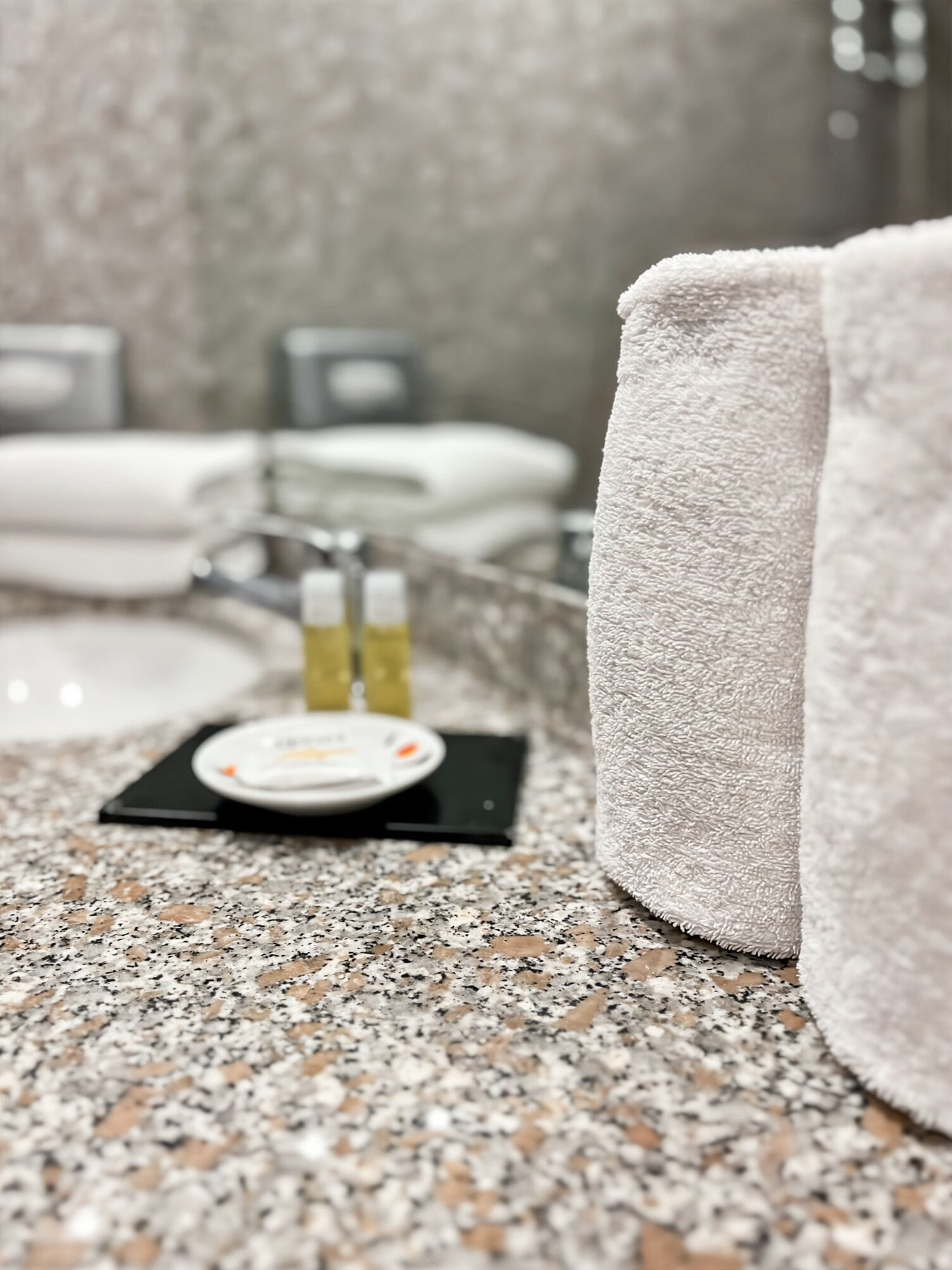 A bathroom with a granite countertop, a towel, and toiletries.