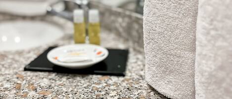 A bathroom with a granite countertop, a towel, and toiletries.