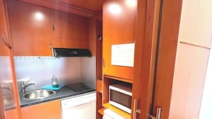 Una cocina compacta con armarios de madera, microondas integrado y lavavajillas.