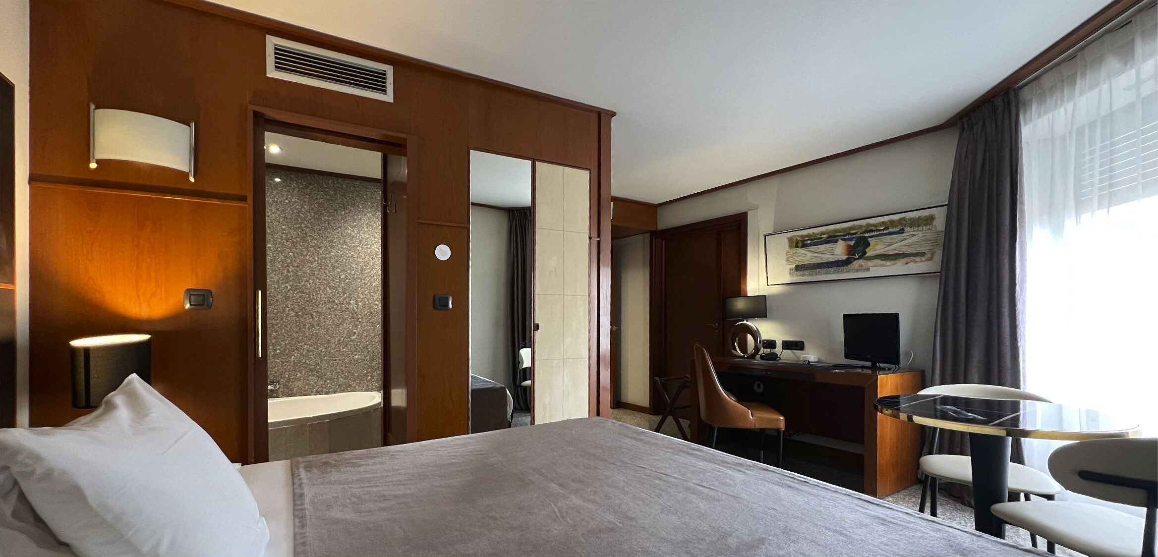 Ein Hotelzimmer mit Bett, Schreibtisch, Stuhl und einem Bild an der Wand.