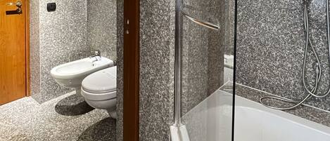 A bathroom with a toilet, bidet, and shower area.