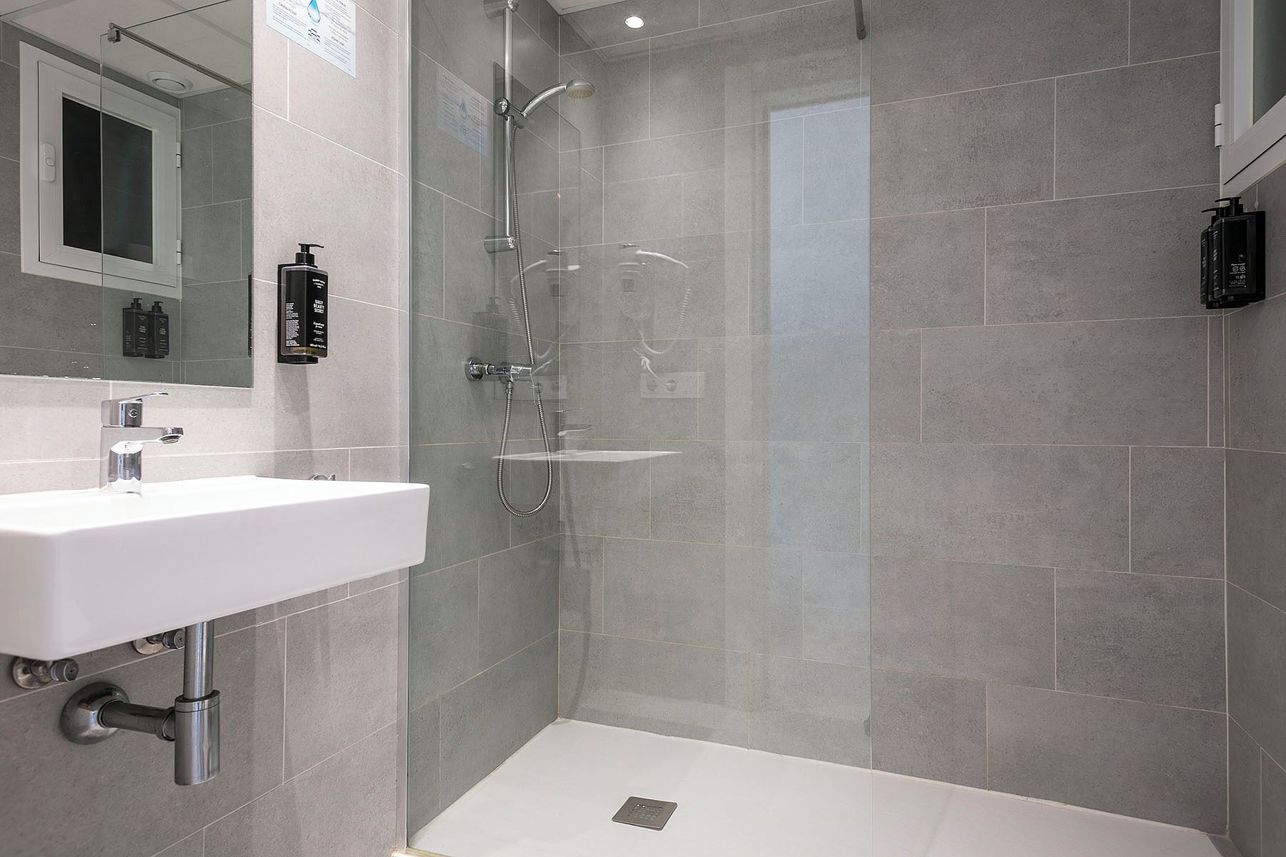 Een moderne badkamer met een douche, wastafel en spiegel.