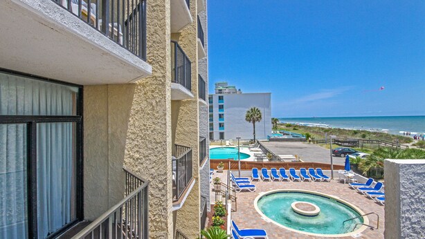 A hotel pool area with lounge chairs and a view of the beach. - Ocean Park Resort by Vacasa (Myrtle Beach)