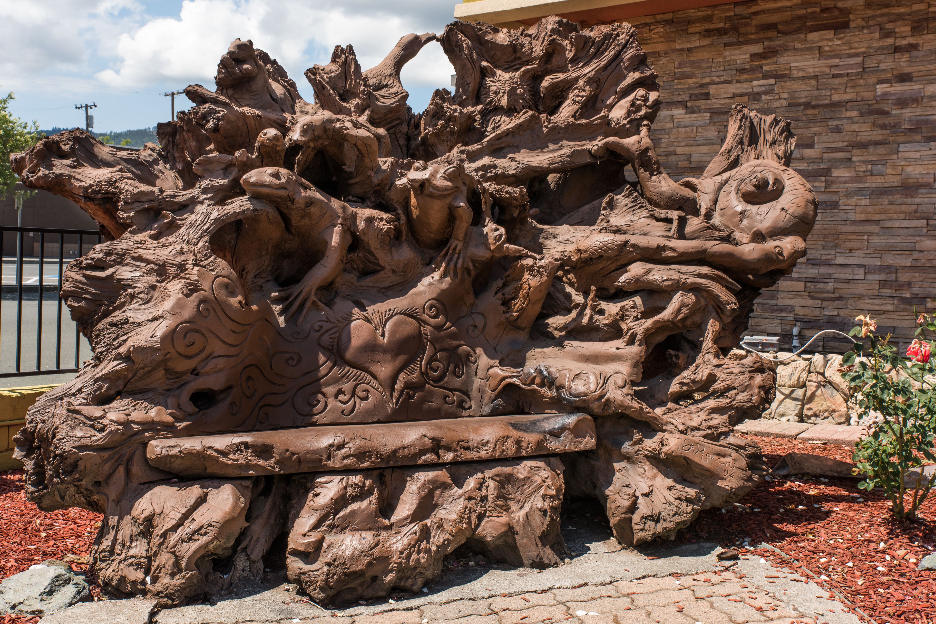 A large, intricate sculpture of intertwined figures and animals, possibly mythological, set against a stone wall.