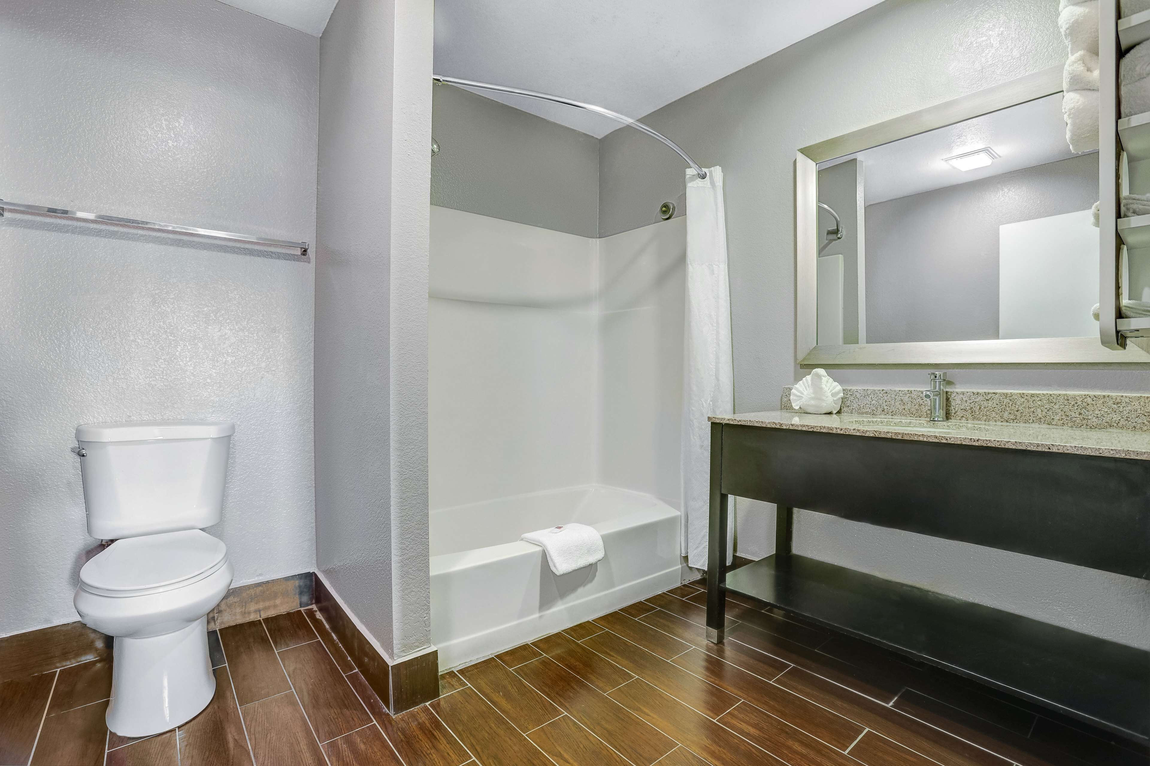 Un bagno con il water, una doccia con porta in vetro e un lavandino con specchio.
