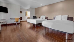 Habitación de hotel con dos camas, un escritorio, una silla y un televisor.