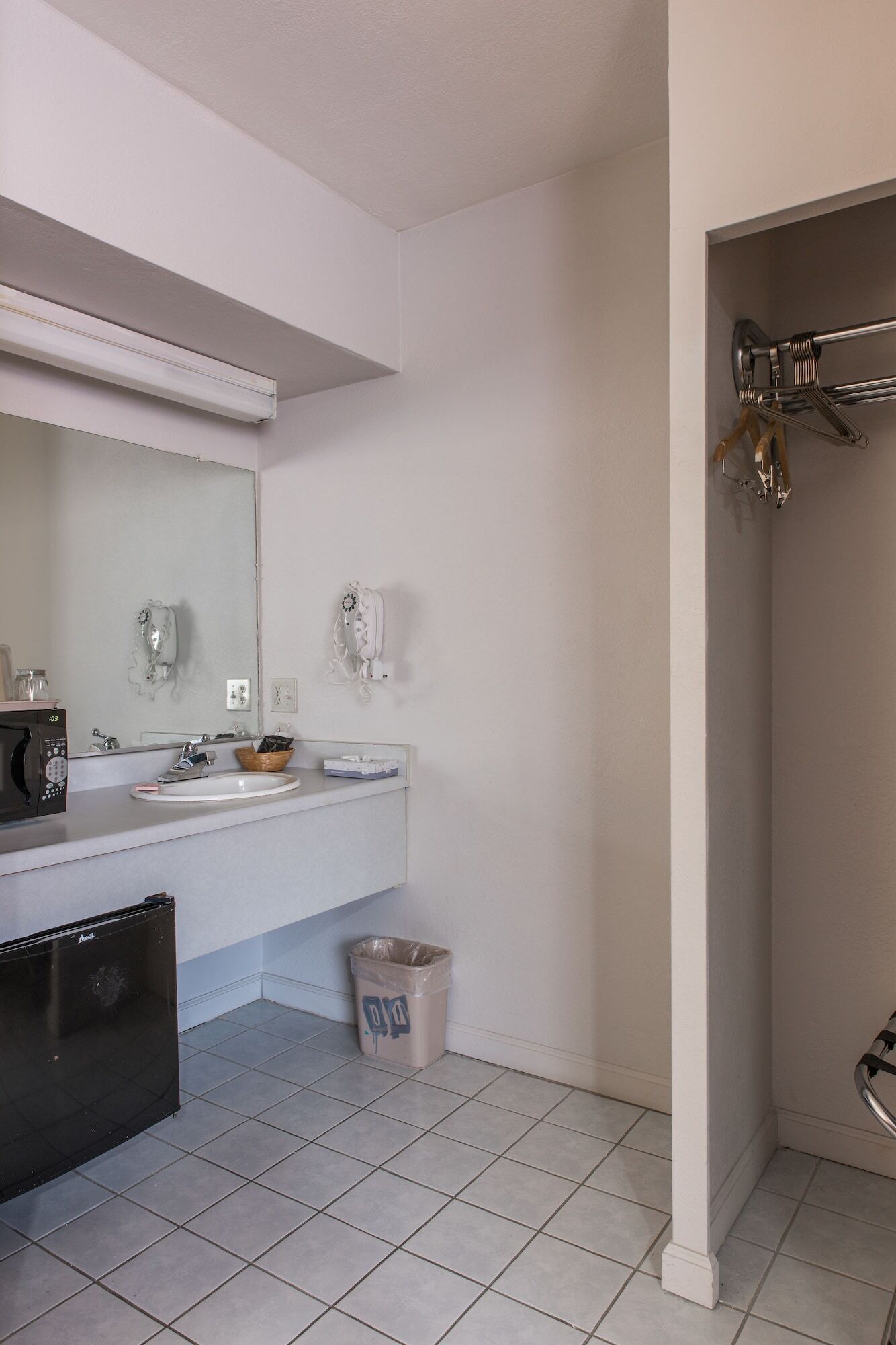 A bathroom with a white sink, a mirror, a hairdryer, and a trash bin.