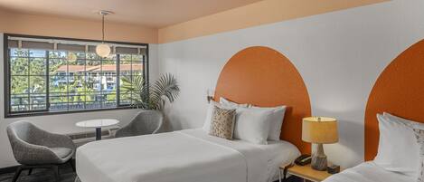 A hotel room with two beds, a small table, a chair, and a view of the outside.