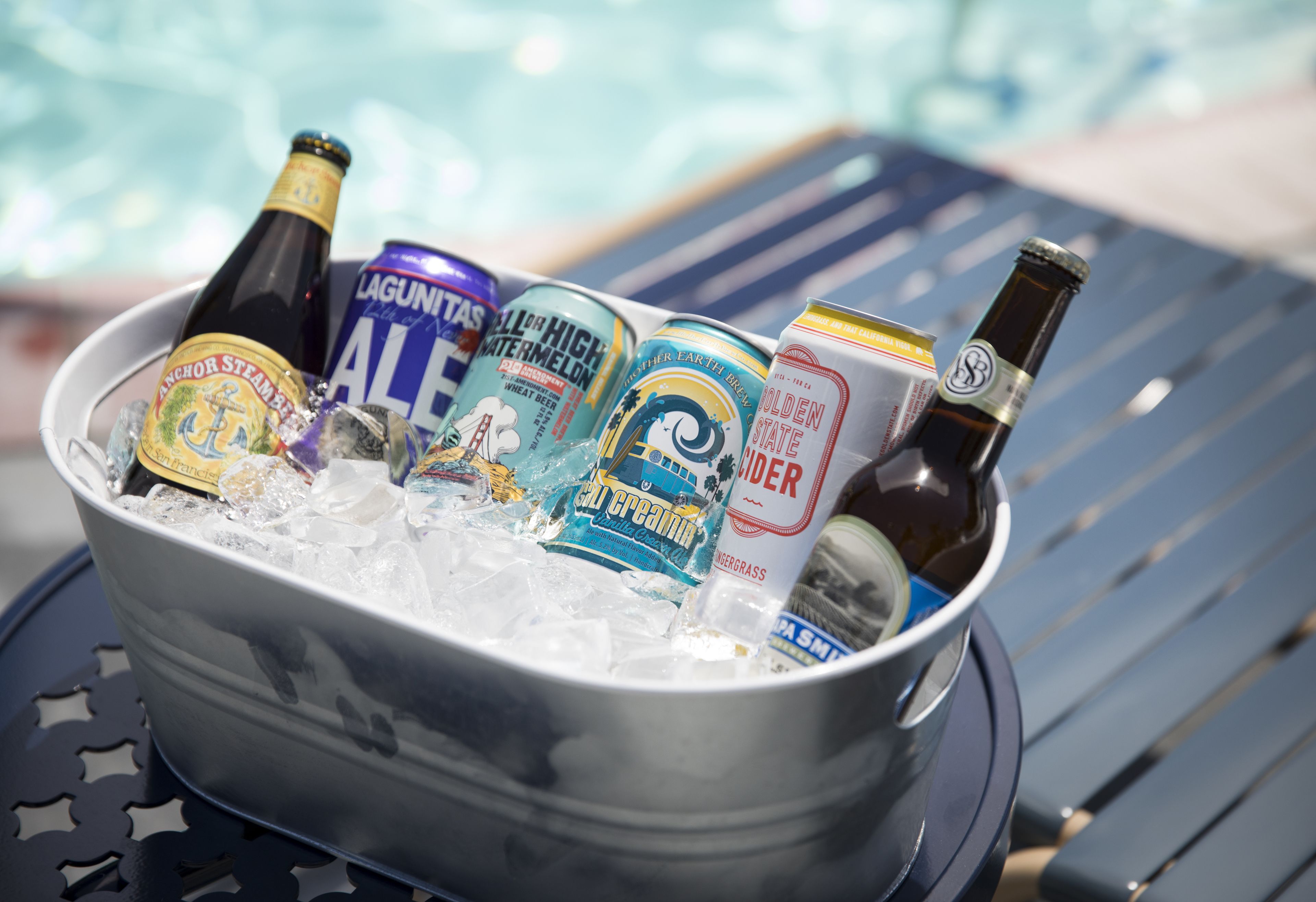 A bucket filled with ice and various beverages including Anchor Steamer, Lagunitas, and Golden State cider.