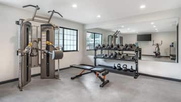 A modern gym with weight machines, benches, dumbbells, and kettlebells.