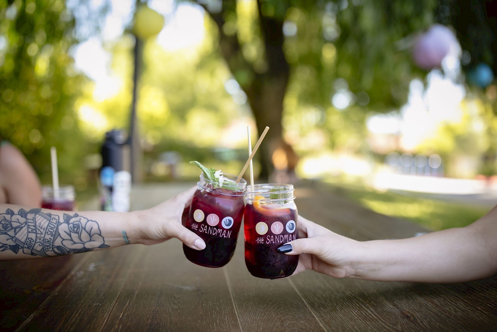 Deux personnes tenant des verres contenant une boisson dont l’étiquette porte l’inscription « The Sandman ».