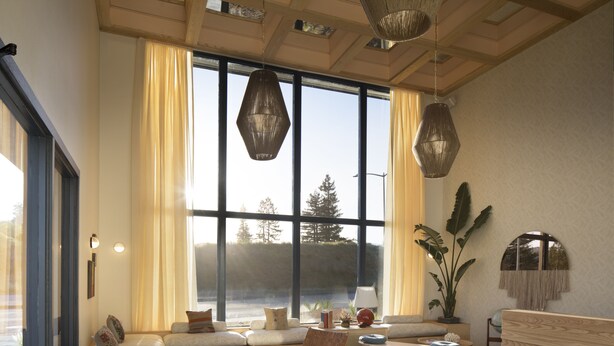 A spacious living room with a large window, a sofa, a coffee table, and a plant. - The Sandman Santa Rosa Sonoma, an Ascend Collection Hotel (Santa Rosa)