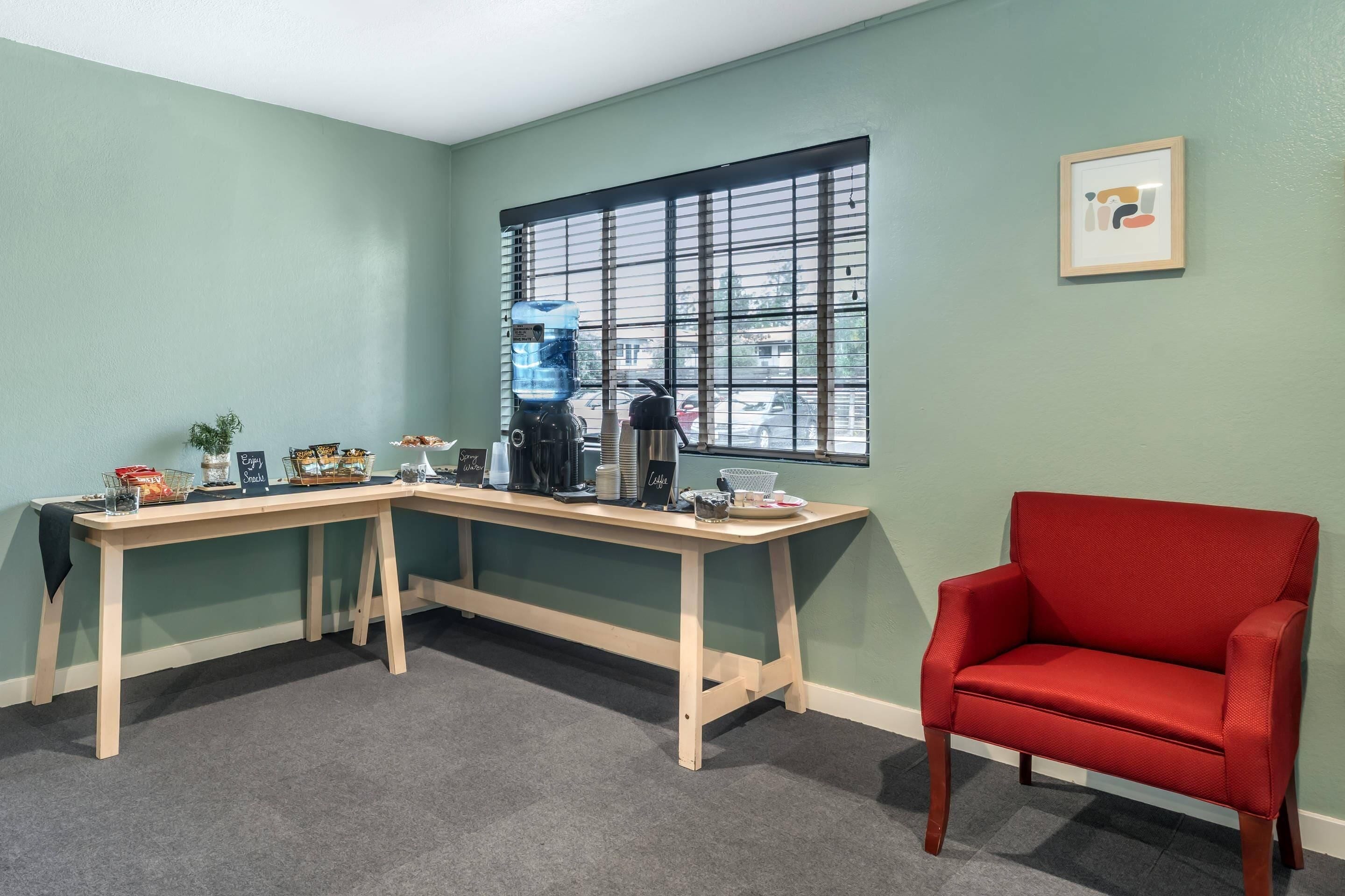 A room with a desk, a red chair, and a window with blinds.