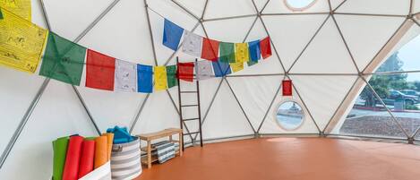 A geodesic dome interior with prayer flags, storage bins, and a ladder.