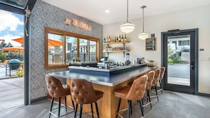 A bar area with a wooden counter, bar stools, and a wine display. - The Sandman Santa Rosa Sonoma, an Ascend Collection Hotel (Santa Rosa)